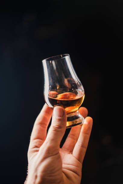 Hand holding a tasting glass of amber American whiskey